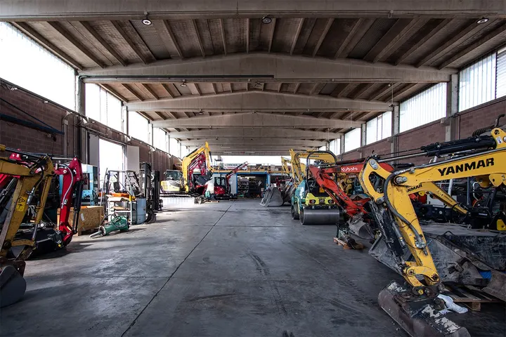 Interno di capannone con flotta di escavatori e macchine movimento terra