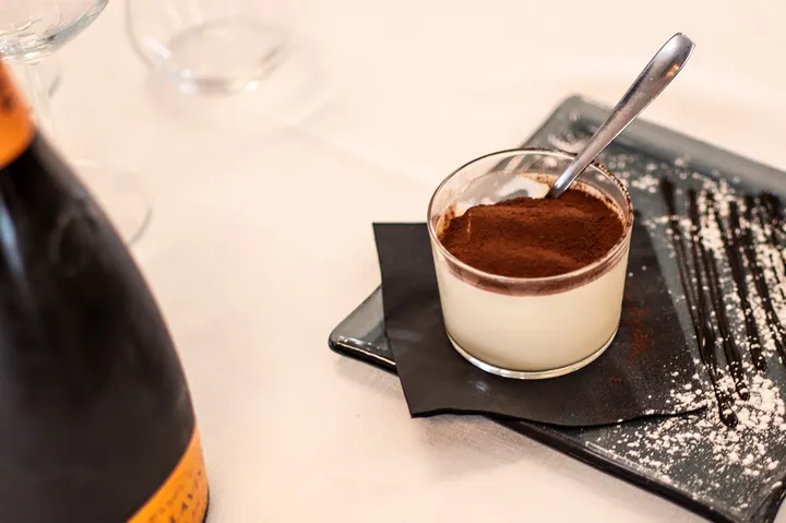Tiramisù in vetro con spolverata di cacao servito su piatto ardesia