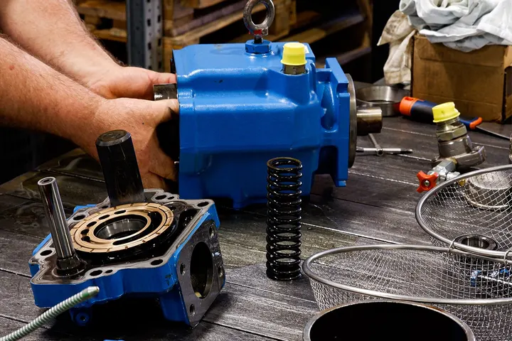 Mani di un tecnico al lavoro su un componente meccanico blu