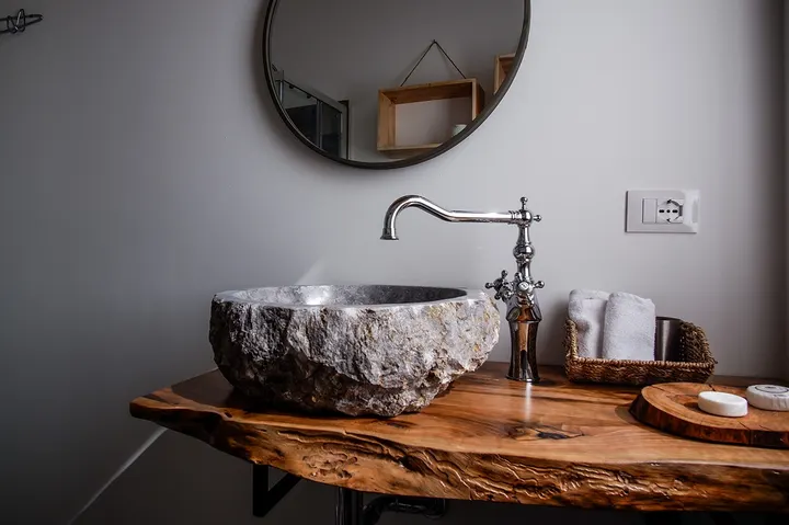 Lavabo in pietra naturale su piano in legno con rubinetteria cromata