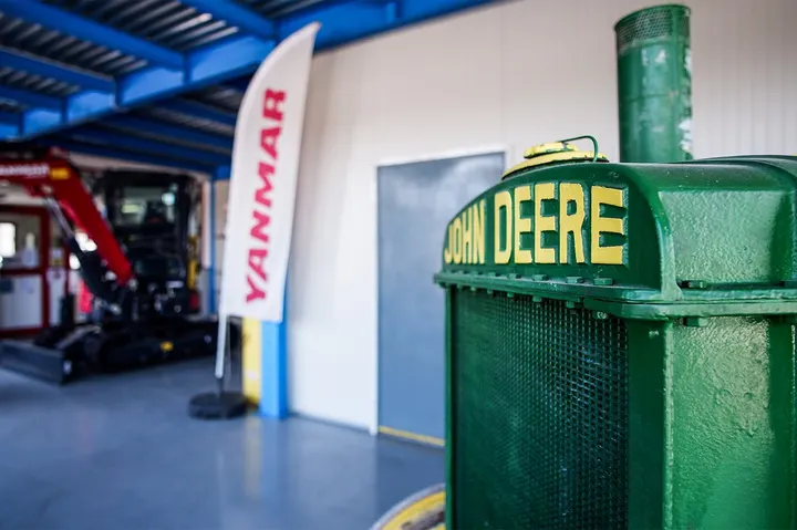 Dettaglio di trattore John Deere in showroom con macchinari Yanmar